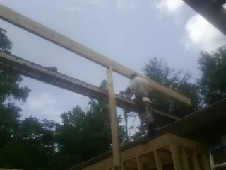 Carpenter setting a ridge beam over a new addition frame — Ice Dam Removal by Roofing Brothers in Gladbrook