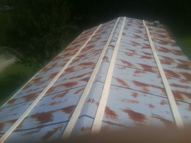 Rusted metal roof panels with new wood purlins before replacement — Storm Damage Roof Repair in Gladbrook by Roofing Brothers