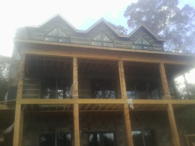 Dormers and porch framing on a large log home under construction — Roof Coating work by our crew in Gladbrook