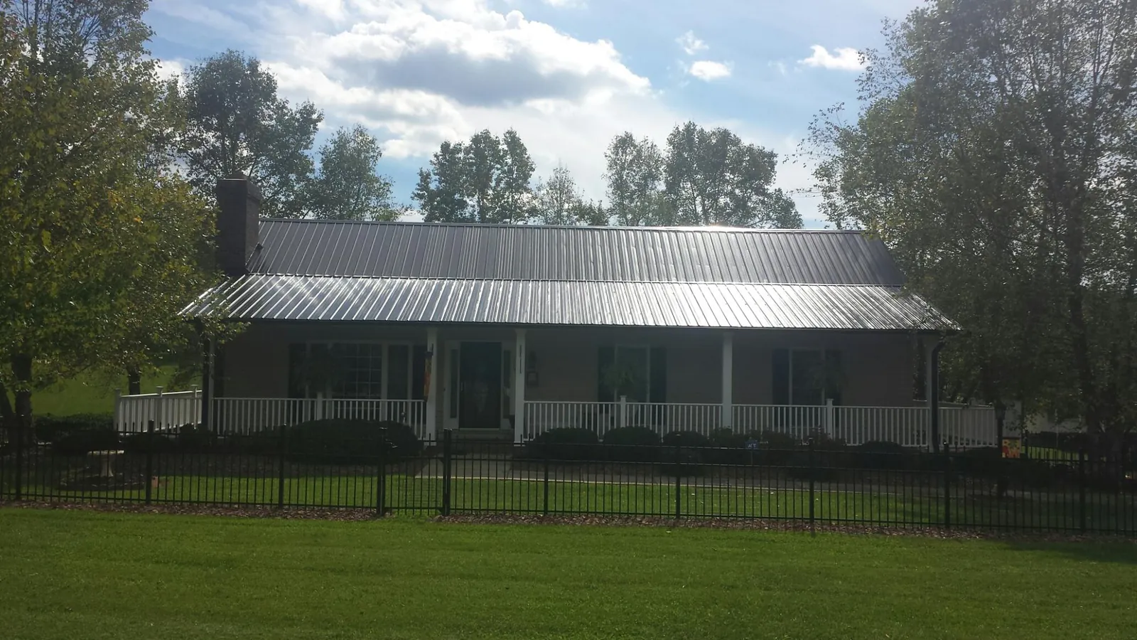 Gray metal roof on a brick ranch with a full width front porch — Gutter Guard Installation work by our crew in Gladbrook
