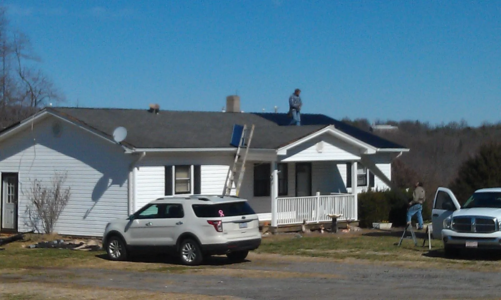 Roofers stripping shingles from a white ranch house roof in Gladbrook