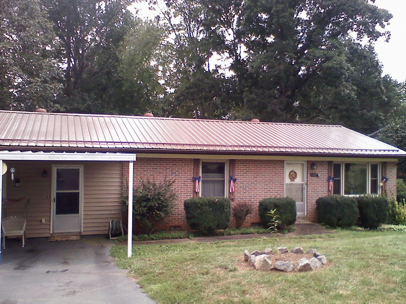 Bronze metal roof and carport on a brick ranch home — Roof Repair work by our crew in Gladbrook
