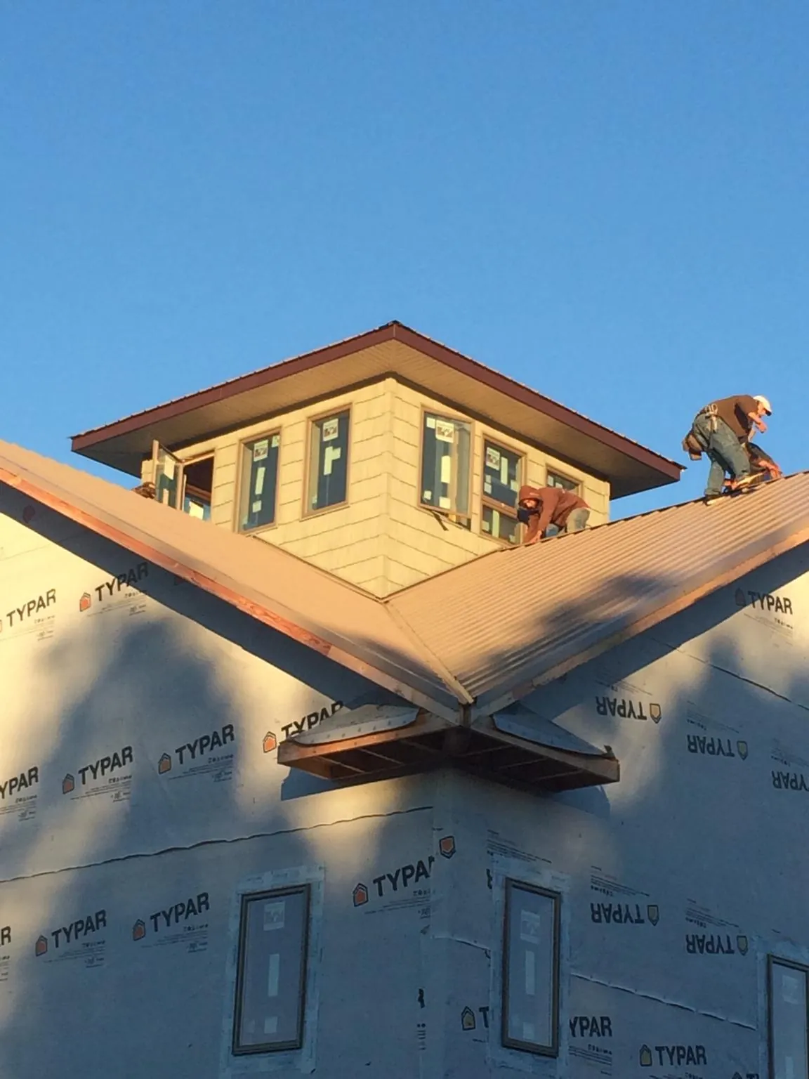 Roofers working around a rooftop cupola on a new metal roof at sunset — Roof Waterproofing in Gladbrook by Roofing Brothers